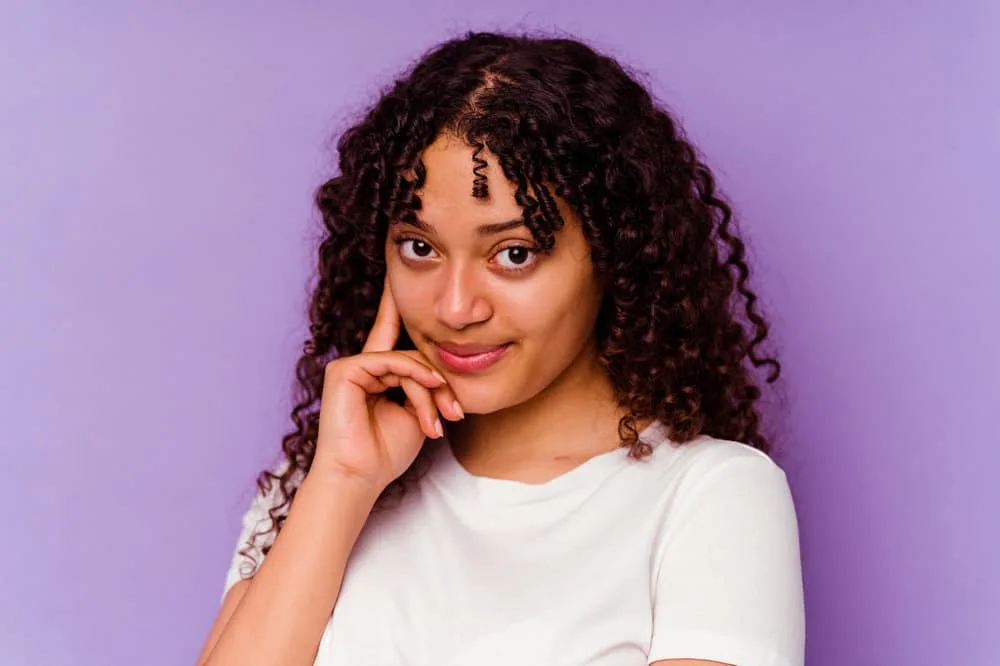 African American female admiring her hair after using rosemary oil for scalp health and hair regrowth.