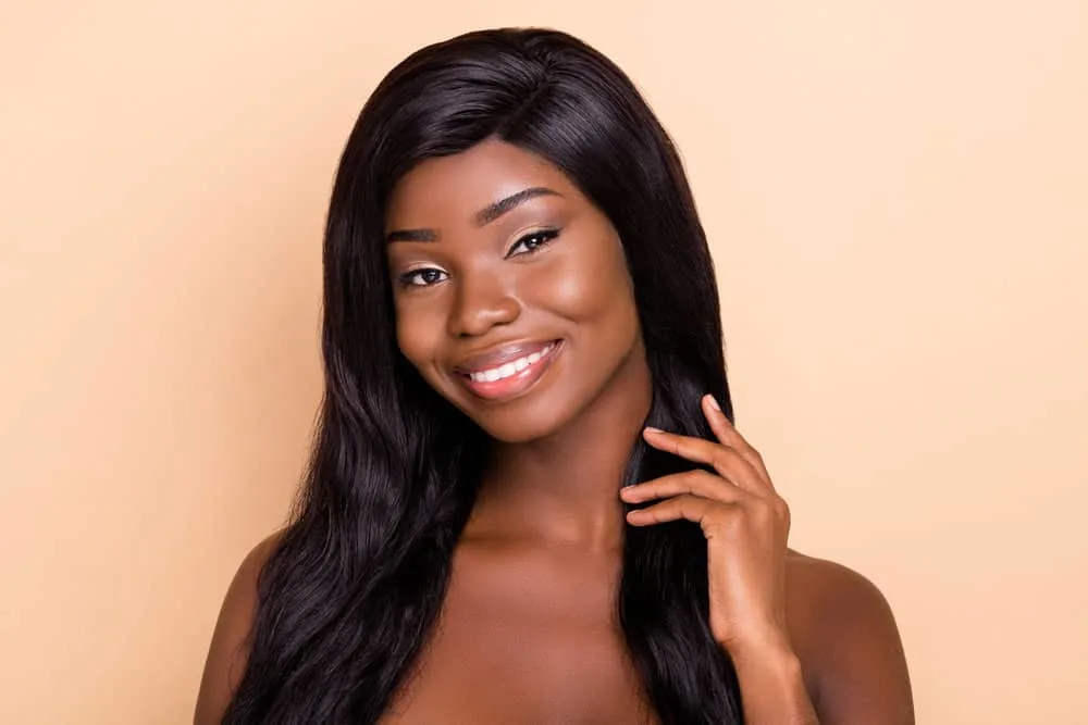 A woman with dark chocolate skin wearing a 150-density wig made from natural human hair texture and light density.