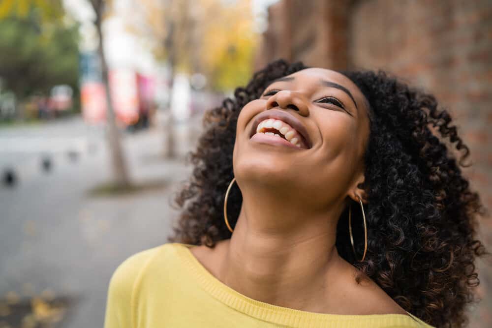 A light-skinned black girl with wavy hair follicles recently dyed dark brown by a professional hair colorist.