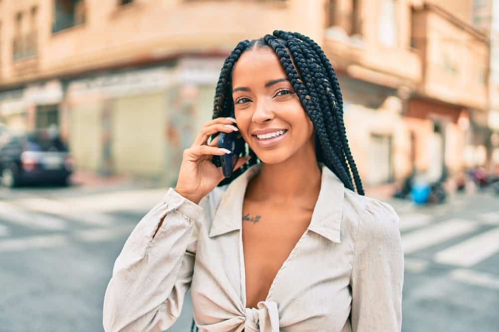 Black girl rope braids wearing a beige shirt walking on the street in downtown Birmingham, Alabama.