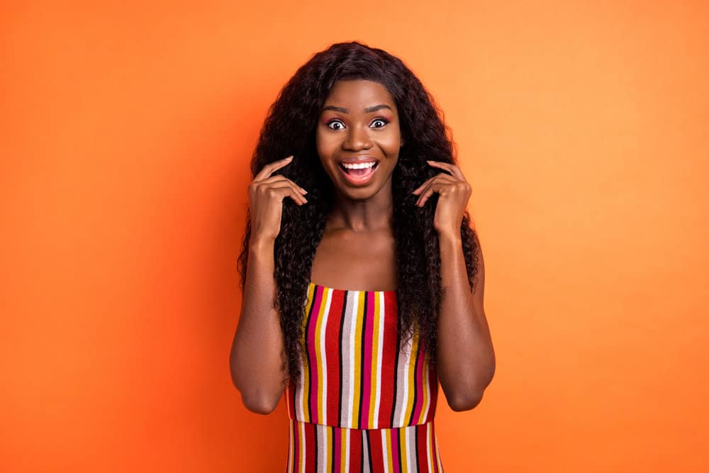 A cute black lady with a middle-back hair length wearing a medium-hair density curly wig.