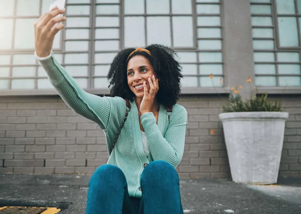 Co-Washing Hair Instead of Shampooing: DIY Step-by-Step 3 A black girl with clean hair following a conditioner washing hair care routine is taking a selfie photo.