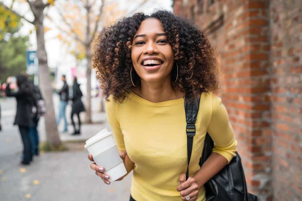 Cute young African American lady with color-treated curly hair researching how to keep her thick hair healthy.