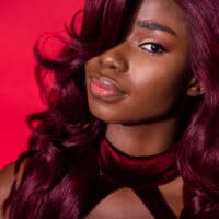 A cute black girl that used regular hair dye on synthetic hair extensions to create a dark red desired color.