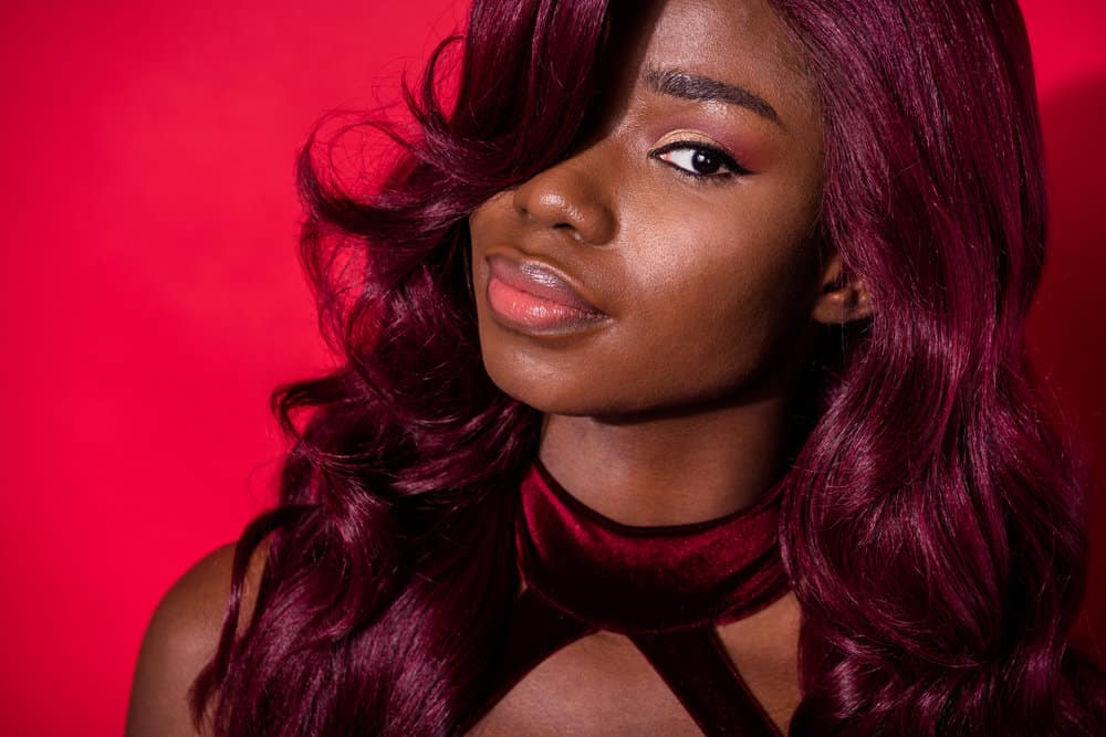A cute black girl that used regular hair dye on synthetic hair extensions to create a dark red desired color.