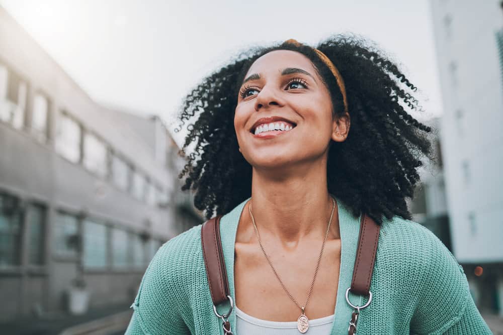 A woman's natural hair is styled with natural oils after co-washing hair with cleansing conditioners (i.e., only conditioner).