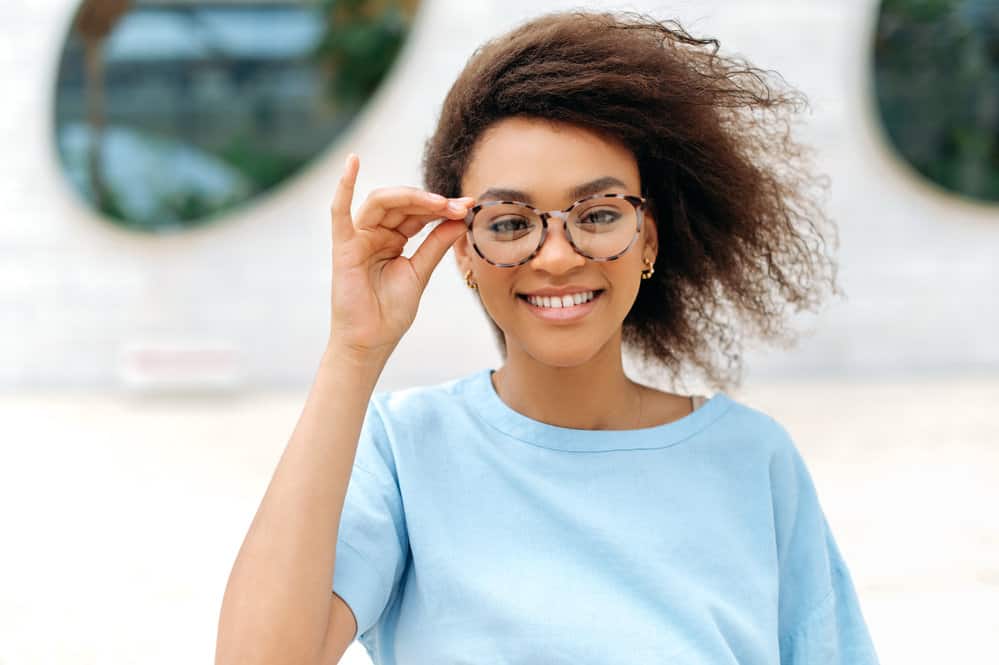 A fashionable black lady wearing stylish glasses after drying her wet hair with a blow dryer and micro-fiber towel.