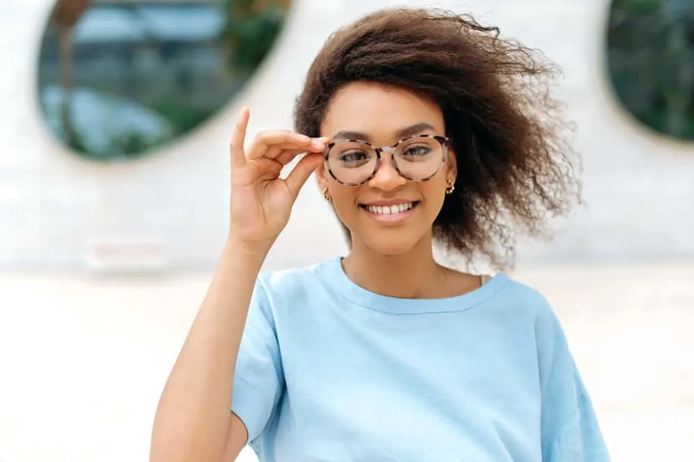 How to Fix Scraggly Hair: Detailed DIY Step-by-Step Guide 9 A fashionable black lady wearing stylish glasses after drying her wet hair with a blow dryer and micro-fiber towel.