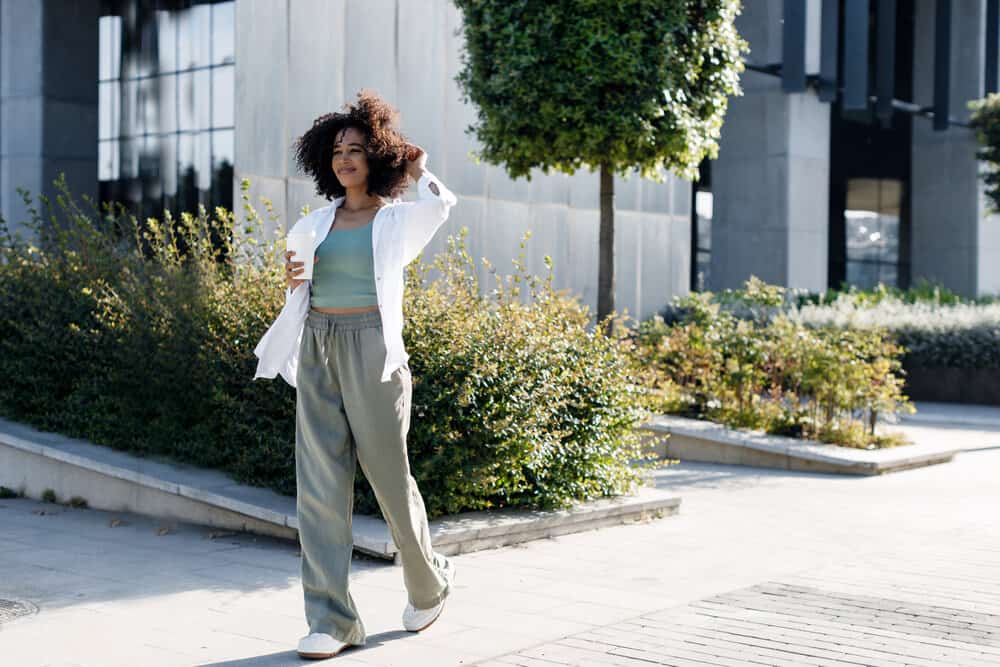 A black girl that's concerned about clogged hair follicles and hair thinning uses natural oils to encourage blood flow.