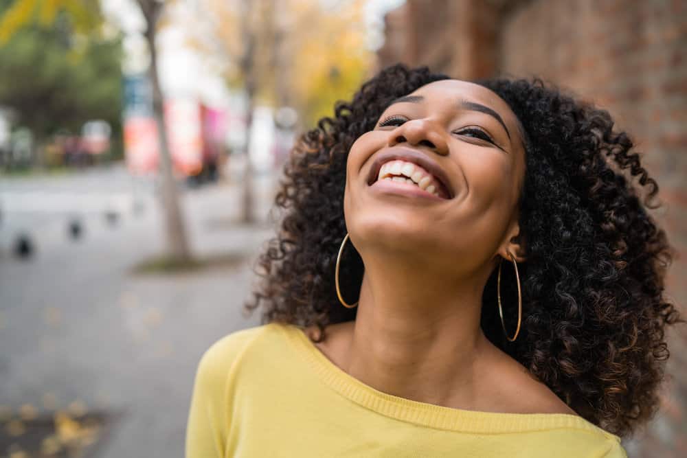 Cute African American female with curly fine hair after using a deep conditioning mask to moisturize her curls.