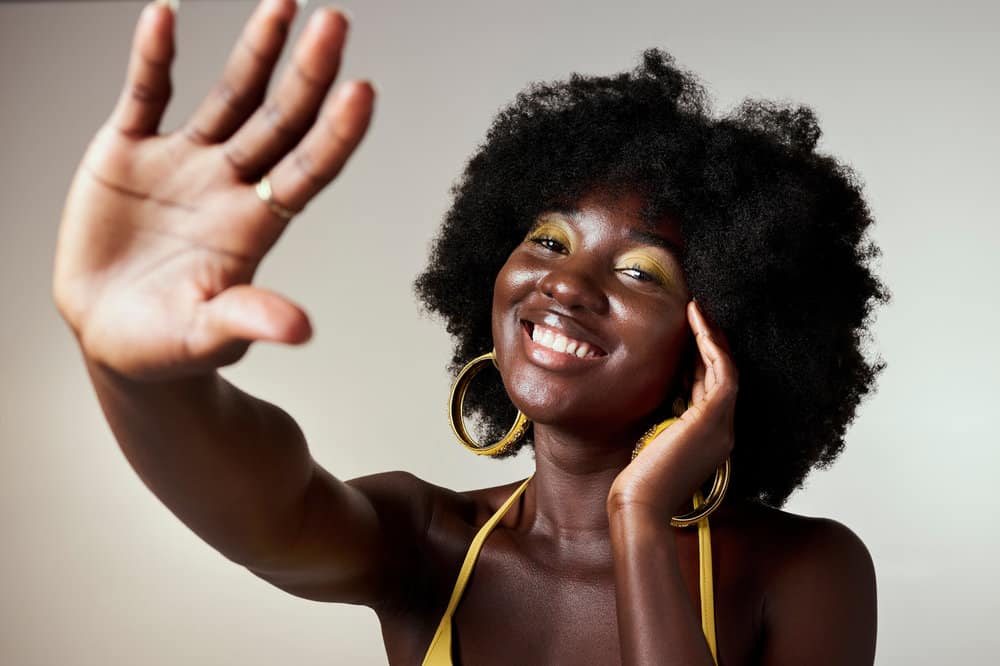 A beautiful African American female wearing an afro style with a thick consistency with excess moisture on her face.