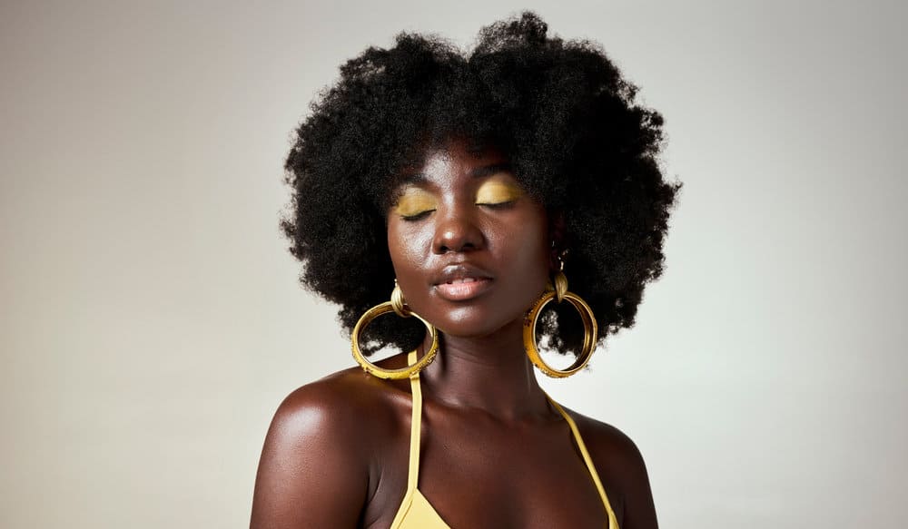 A black girl focused on scalp and hair health regularly uses a hot oil treatment when hydrating low-porosity hair.