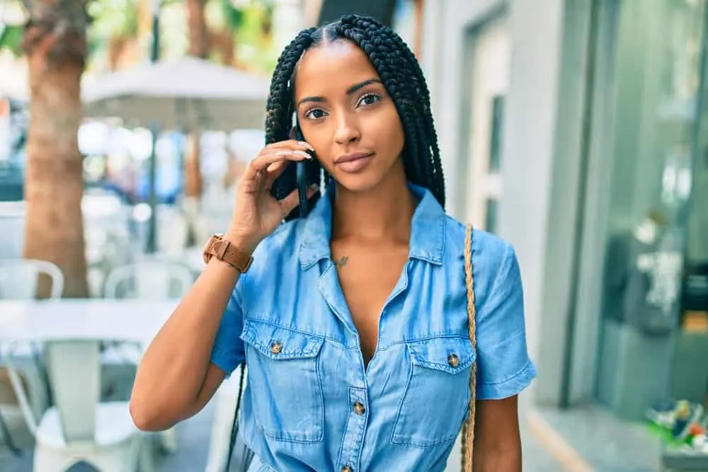 American female standing outside talking on the cell phone at a restaurant.