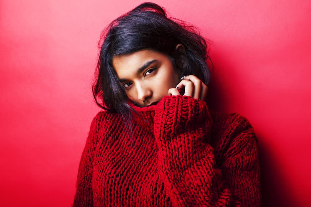 An Indian female with long hair has an oily scalp from co-washing hair with almond oil, encouraging hair growth.