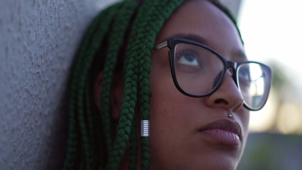 A black woman with tight braids has been experiencing traction alopecia, scalp dryness, and excessive itching.