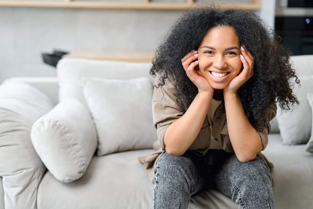 A cute black woman with wavy hair showing off her natural curl pattern after using the finger comb method.