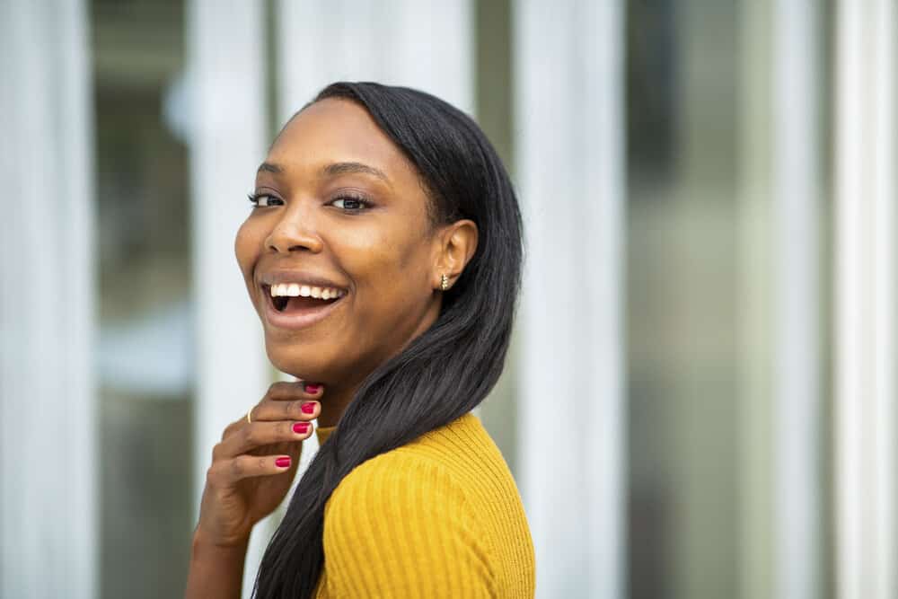 African woman with split ends and environmental damage on her straight hair due to heat-focused hair care routine.