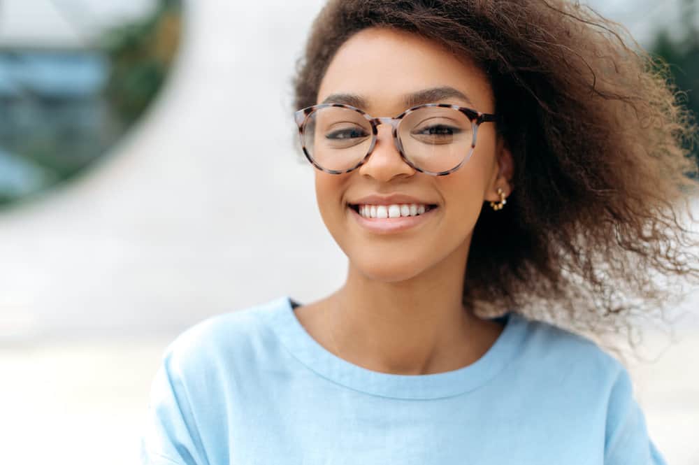 A charismatic African female with naturally wavy hair has lifeless locks after heat damage caused thin hair strands.