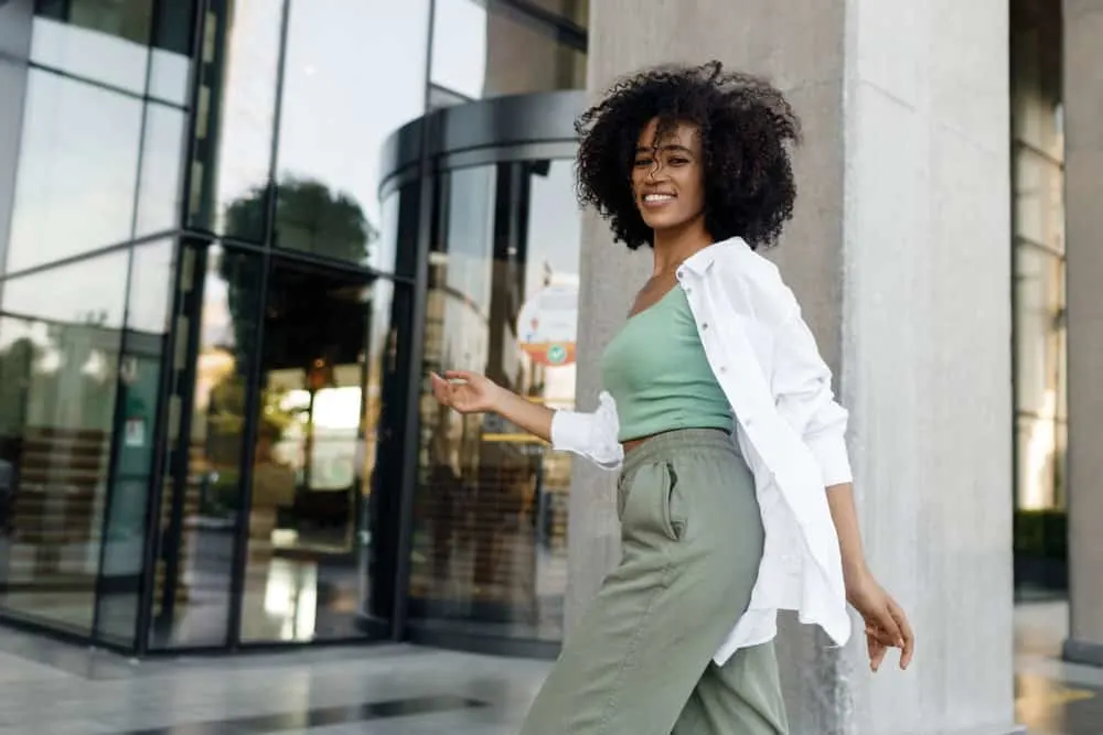 Does Curly Hair Shed More Than Straight Hair? How to Stop It? 5 A happy black girl with bouncy curls after fixing her hair, shedding where the hair follicle naturally falls out.