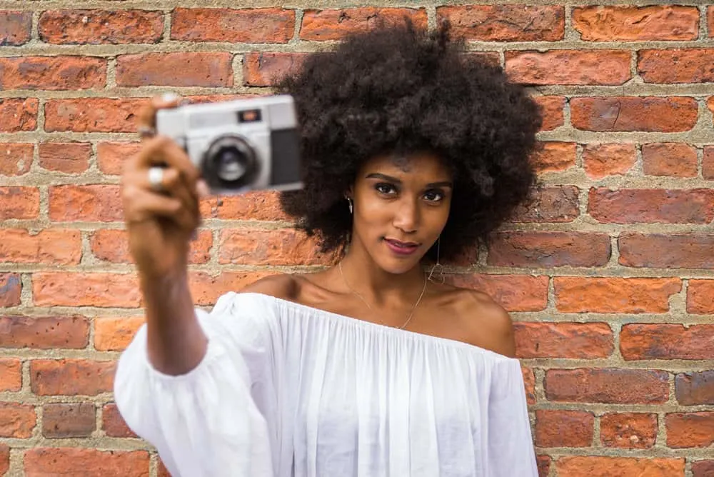 A black girl with a beautiful complexion has dry hair styled with a leave-in conditioner that contains coconut oil.