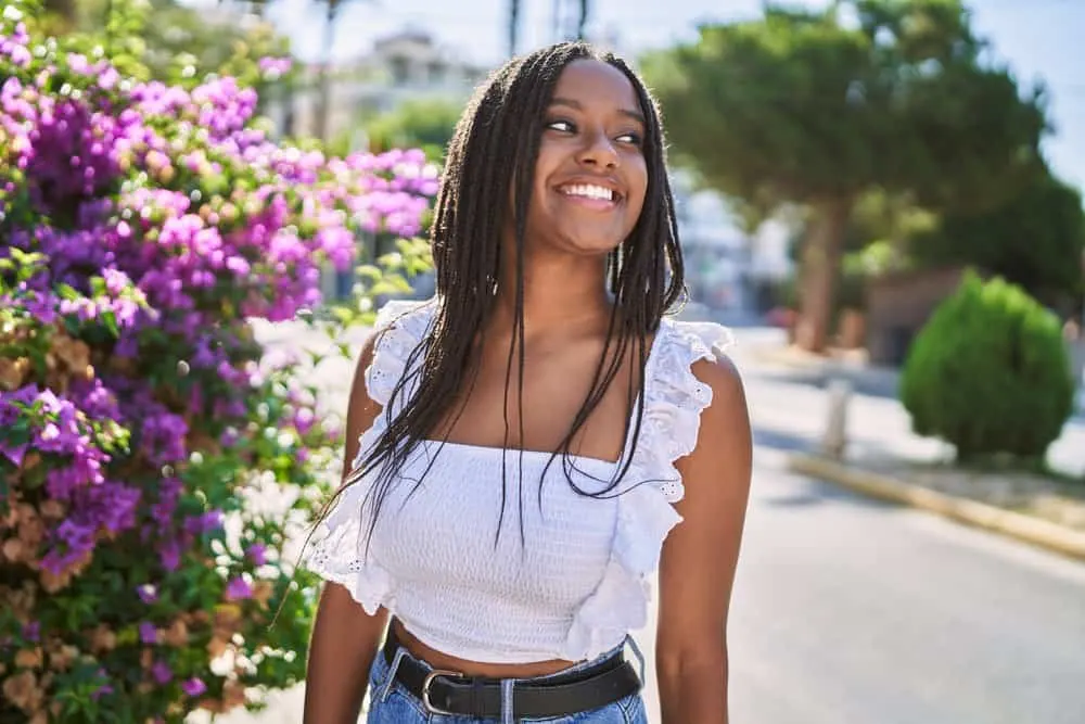 A cute black female within the natural hair community is wearing a freshly braided hairstyle with a casual outfit.