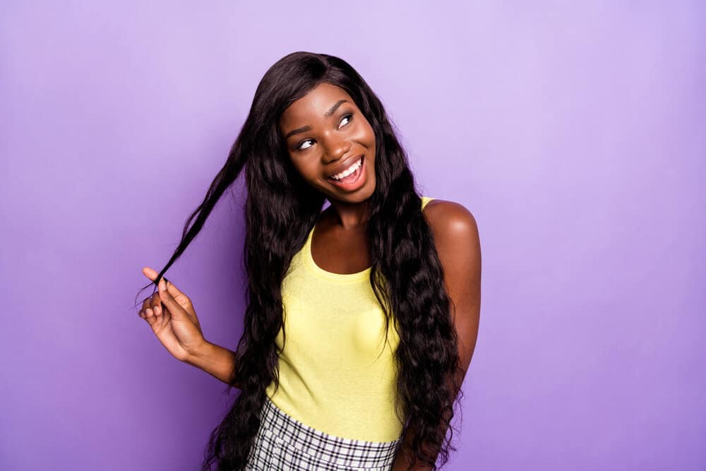 A cute black girl wearing a lace front wig made of human hair creates a natural hairline that lasts up to six weeks.