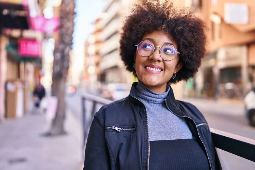 How to Care for Low-Density Curly Hair: DIY Step-by-Step 4 A stunning black woman with wavy hair that was cleaned with dry shampoo and styled with curl creams to reduce frizz.
