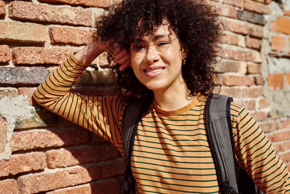 A young black woman with lifeless hair that was treated with a protein treatment and styled with olive oil.