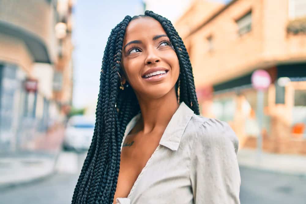 A cute black girl with naturally curly and coily hair wearing goddess locs with hair cuffs, beads, and a center part.