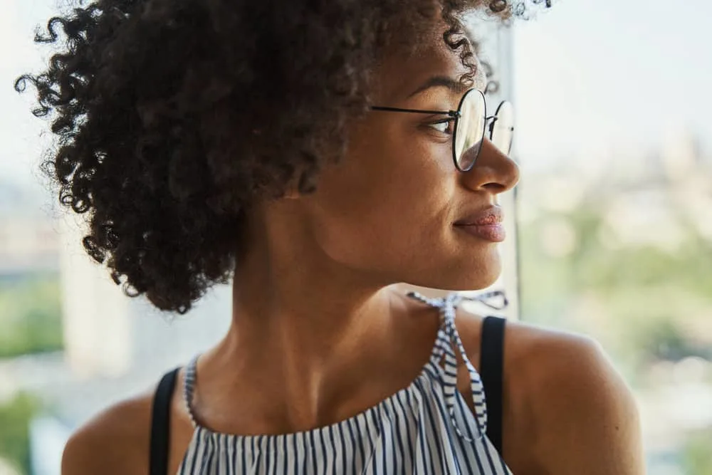 Curly Girl Method: How to Guide, CG Method Steps & Products 3 An African American woman that is following the CG Method dried her wet hair with a microfiber towel.