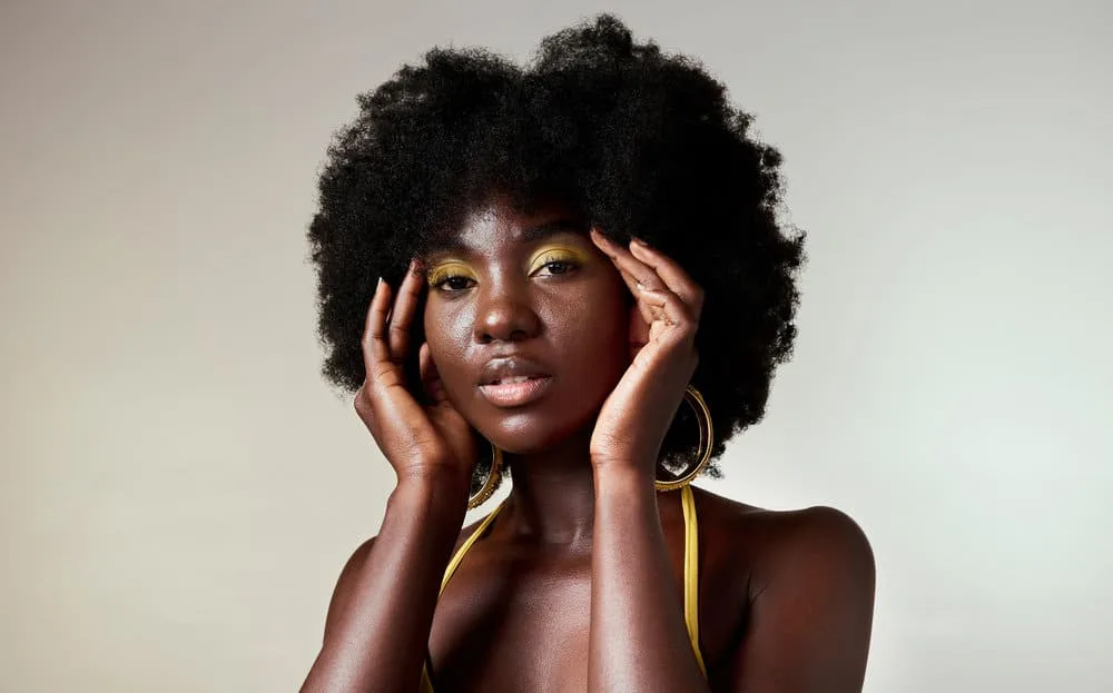 A cute female wearing natural-looking makeup used an apple cider vinegar rinse to wash low-porosity hair stands.