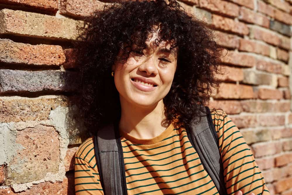 A cute black girl with curly and wavy hair washed with traditional shampoo and styled with natural oils.