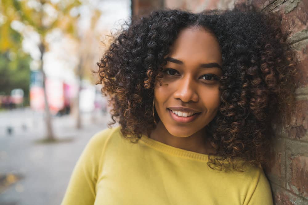 Black girl with frizzy hair on the title image of an article about how to deep condition hair.