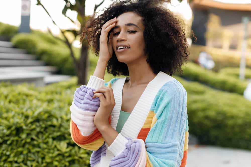 A black woman with curly hair has product accumulation and used detox shampoo to remove hair product buildup.