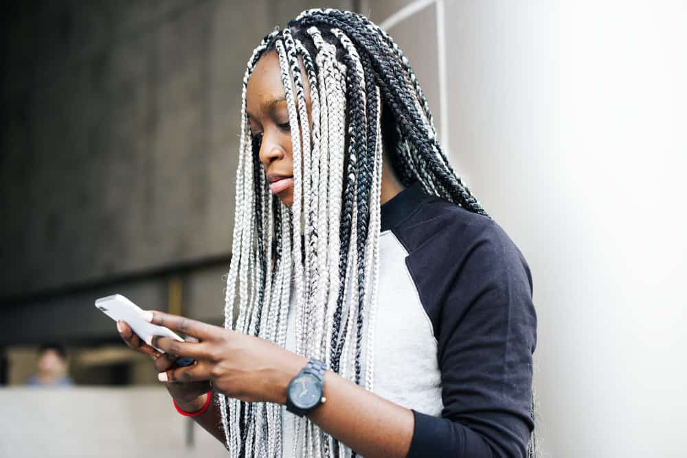 A stylish black girl with braided synthetic hair styled with lightweight hair products to prevent acne and product buildup.