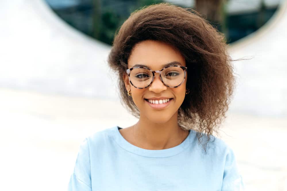 A beautiful black girl with stringy hair strands that have been cleaned with dry shampoo and styled with natural oils.