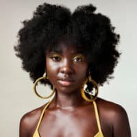 A black woman with low porosity natural hair that's been styled with rice water and aloe vera to encourage healthy hair.