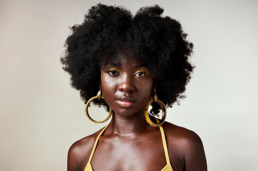 A black woman with low porosity natural hair that's been styled with rice water and aloe vera to encourage healthy hair.