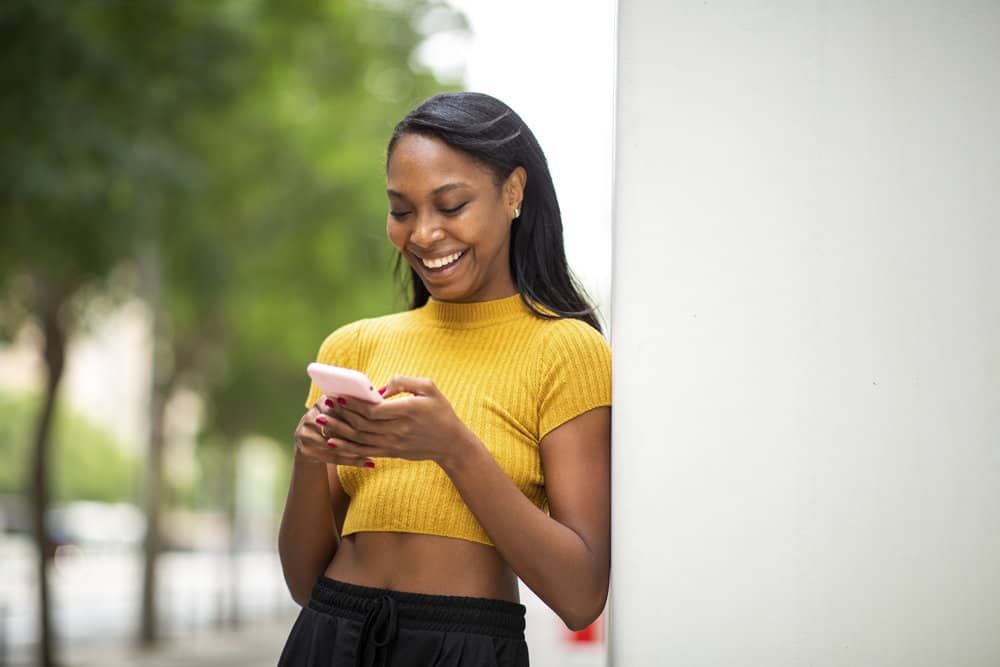 A woman with naturally curly hair is researching the Curly Girl Method on her phone to revive her curly hair type.