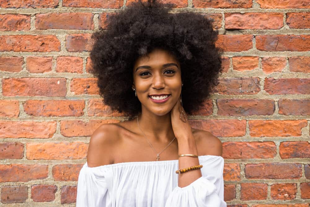 A black female with natural hair strands in a wash-and-go style highlighting her curl pattern and wiry textured hair.