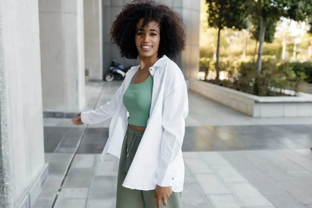 Does Curly Hair Shed More Than Straight Hair? How to Stop It? 4 A black female wearing a wash-and-go hairstyle on her thinning hair caused by chemical-laden hair products.