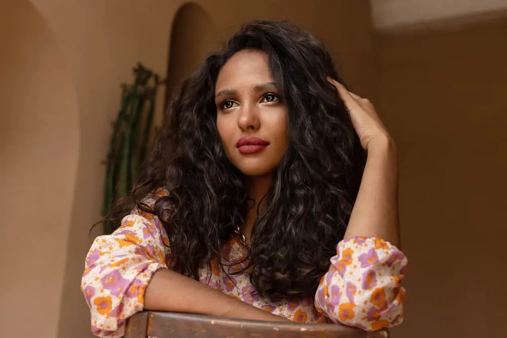 Ayurvedic Hair Growth: How to Use Ayurveda Hair Oil & Herbs 5 A dark-skinned female with dark brown curls styled with natural hair oils to boost hair growth and mitigate hair fall.