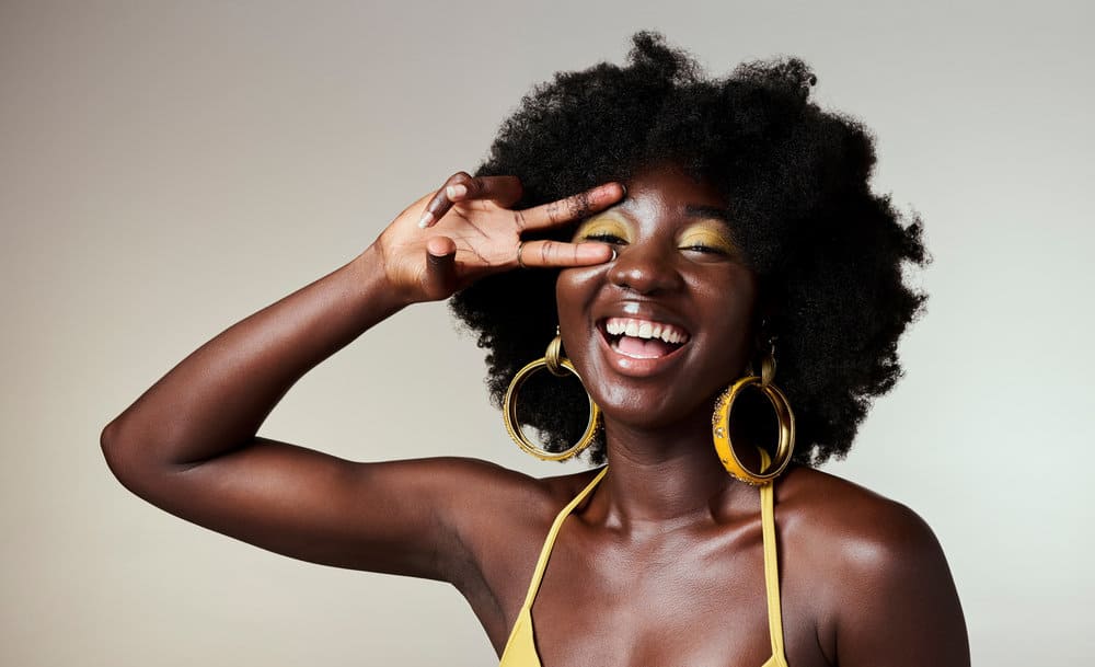 A cute black girl with high porosity hair moisturizes her hair regularly with avocado oil to promote hair growth. 