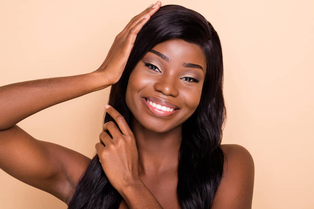 A cute young African American female that's a lace wig lover wearing a black wig made of long straight hair.