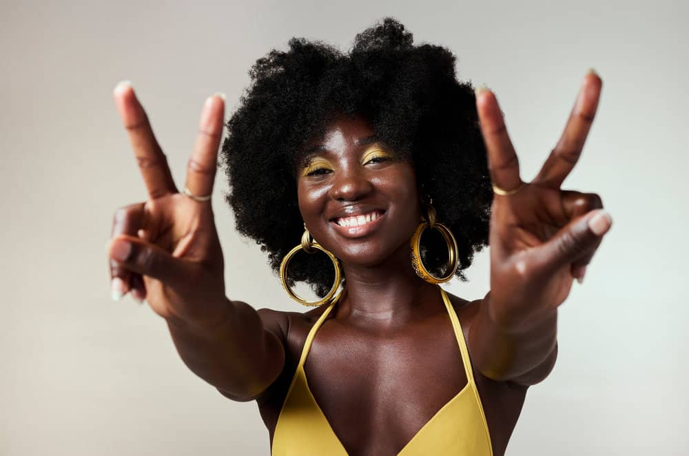 A black female focused on growing low-porosity hair uses scalp massages to encourage blood flow and scalp health.