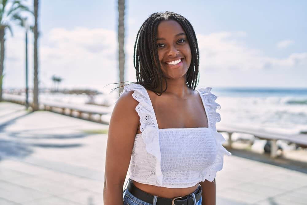 A young black girl with round facial features is wearing her versatile black hair in a cute braided hairstyle.