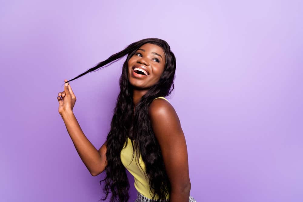 An African female is wearing a synthetic wig with a natural-looking hairline even in direct sunlight.