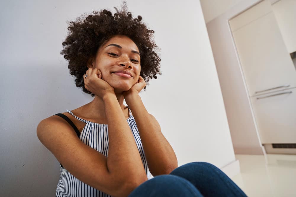 African American female that's following the curly hair method keeps their hair curly by avoiding hot tools.