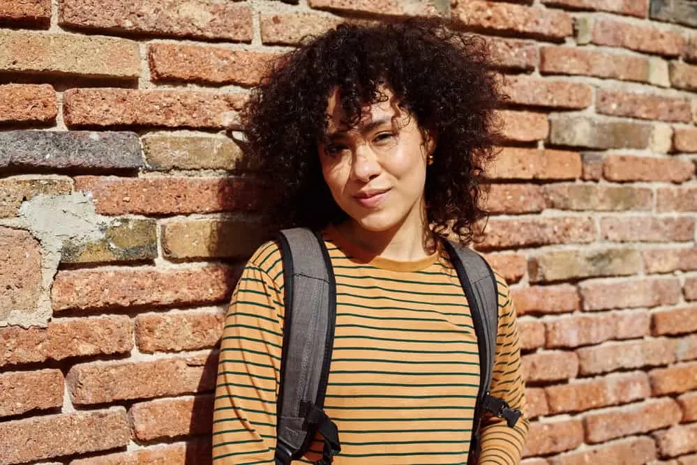 How to Clarify Curly Hair at Home: DIY Clarifying Guide 4 A beautiful female on her curly hair journey used a clarifying wash to mitigate her oily hair and flaky scalp.