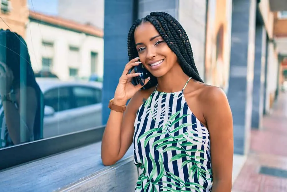 African American woman with 4C hair type wearing Ghana Braids and green, blue, and white shirt.